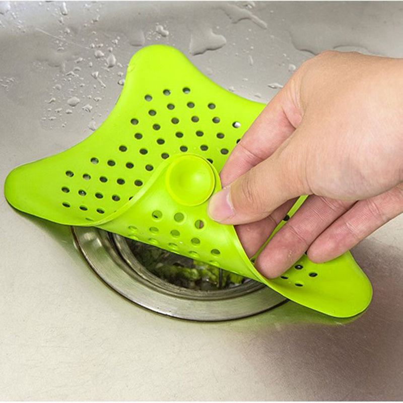Green sink strainer being held over a sink drain