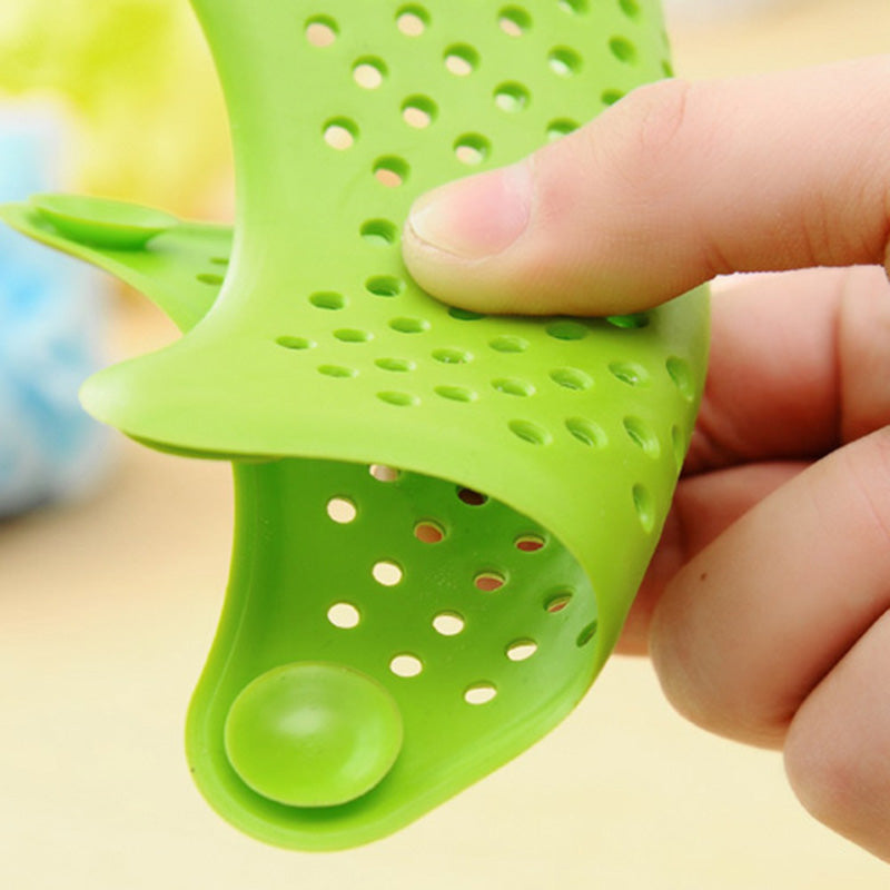 Green silicone strainer held by a hand against a blurred background